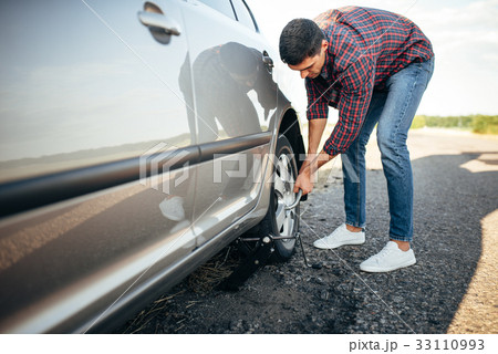 Male person hands with wheel wrench, broken car Male person hands with wheel wrench, broken car 33110993