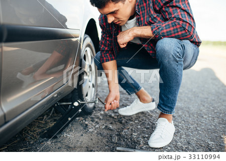 Man jack up broken car, wheel replacement 33110994