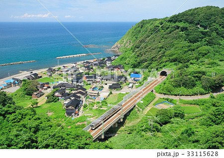 トンネルを抜け真夏の海岸線を走る信越線E129系普通電車 33115628