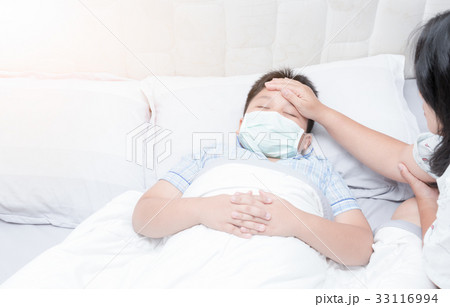 Sick boy with hygienic mask laying on bed 33116994