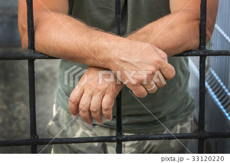 hands of a man behind bars prisons 33120220