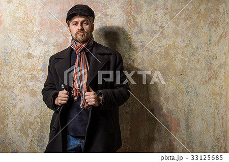 man  dressed warmly in a stylish black trench coat 33125685