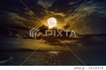 Rising yellow full moon in dark night sky Rising yellow full moon in dark night sky 33134278