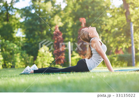 Young woman practicing yoga outdoors at the park 33135022