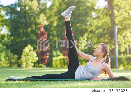 Young woman practicing yoga outdoors at the park 33135023