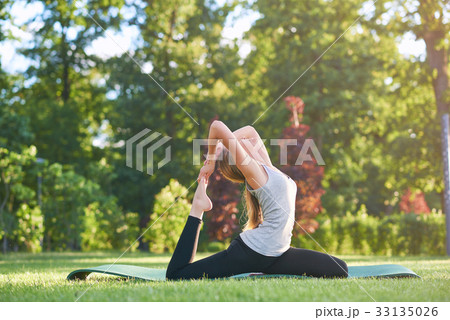 Young woman practicing yoga outdoors at the park 33135026