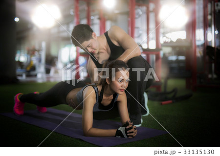 Asian trainer and lady take personal training in fitness club 33135130