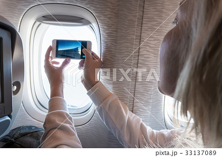 Blond young woman filming video inside plane 33137089