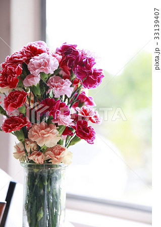 窓辺の花瓶に生けられたカーネーションの花束の写真素材