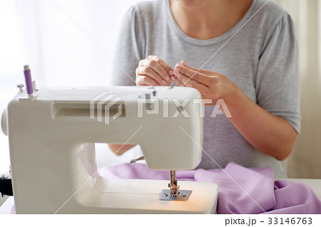 woman with spool of thread and sewing machine 33146763