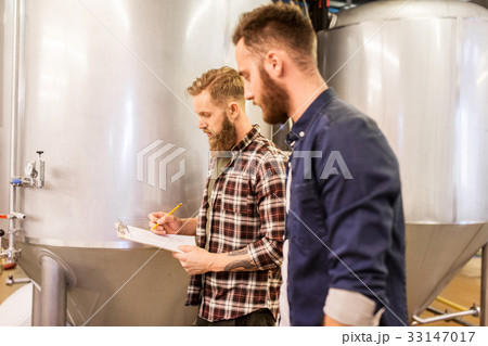 men with clipboard at craft brewery or beer plant 33147017