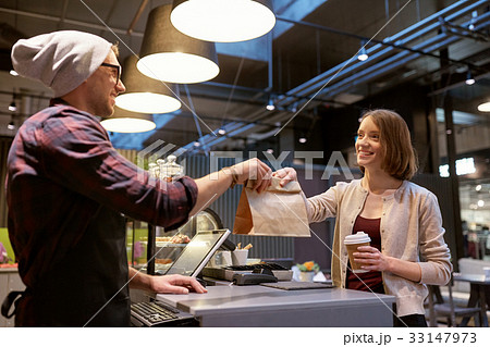 woman taking paper bag from seller at cafe 33147973
