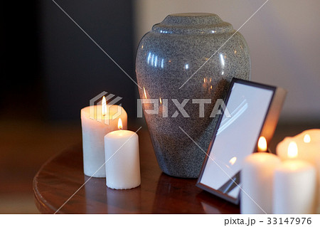photo frame, cremation urn and candles on table 33147976