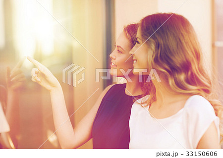 happy young women pointing finger to shop window happy young women pointing finger to shop window 33150606