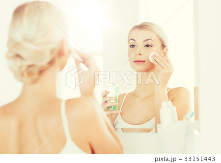 young woman with lotion washing face at bathroom 33151443