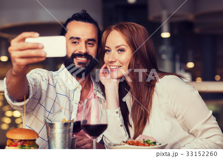 couple taking selfie by smartphone at restaurant couple taking selfie by smartphone at restaurant 33152260