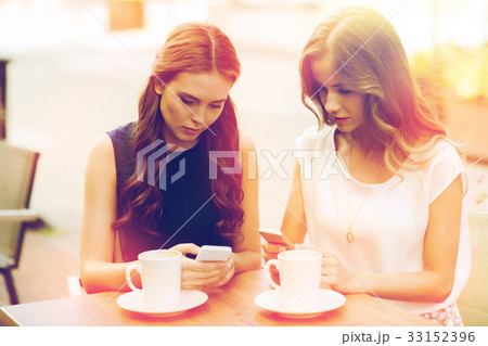 women with smartphones and coffee at outdoor cafe 33152396