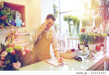 man with smartphone making notes at flower shop 33152431