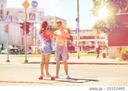teenage couple riding skateboards on city street 33152460