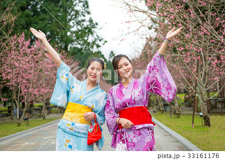 Two women open arms with cherry-blossom 33161176