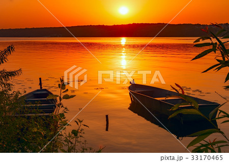 Two fishing boats moored near the shore of a pond 33170465