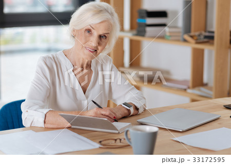 Delighted aged businesswoman sitting at the table 33172595