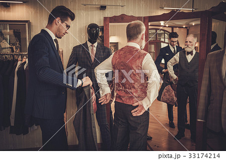 Tailor and client measuring custom made garment 33174214