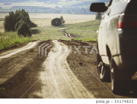 A car next to a winding dirt road A car next to a winding dirt road 33174822
