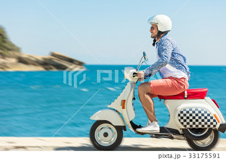 Handsome man posing on a scooter in a vacation 33175591