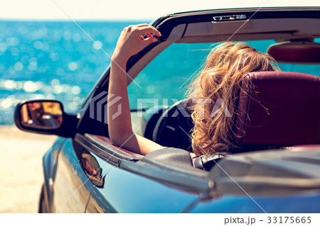 Beautiful blond smiling young woman in convertible 33175665