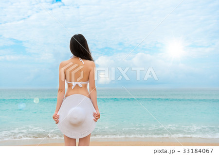 young woman standing on the beach with white hat young woman standing on the beach with white hat 33184067