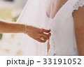 Woman fixes dress on bride's back 33191052