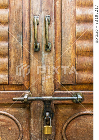 Old latch and padlock on a wooden door Old latch and padlock on a wooden door 33195217