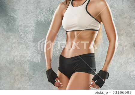 Muscular young woman athlete posing at studio 33196995