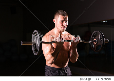 young man doing heavy weight exercise for biceps. young man doing heavy weight exercise for biceps. 33197096