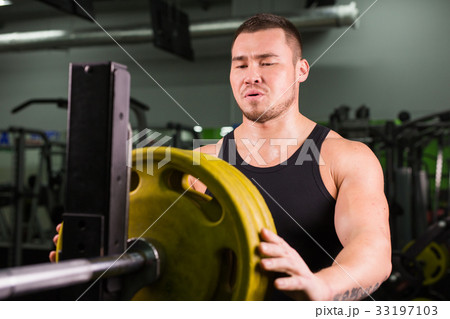 Young sportsman preparing his barbell by twisting 33197103