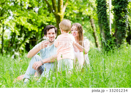 Little boy running over meadow with family in back 33201234