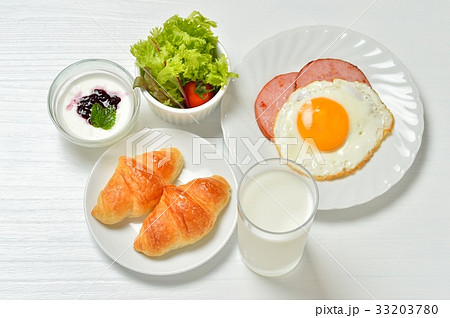 朝食のクロワッサンとミルク、目玉焼き、ハムソテー、ミニサラダ、ヨーグルト。※湯気は合成。 33203780