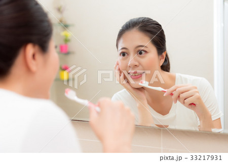 smiling holding toothbrush and hand put on chin 33217931
