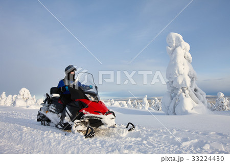 Man driving snowmobile in snowy mountain valley 33224430