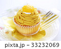黄色い甘栗の乗ったカップケーキサイズの市販のモンブラン　フォークを添えて 33232069