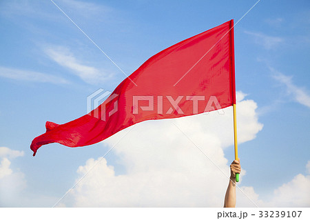 Hand waving a red flag with blue sky background 33239107
