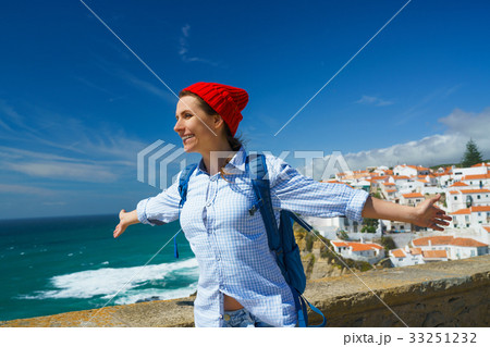 Woman with a backpack is spinning her arms out 33251232