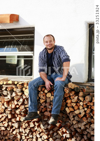 Happy farmer takes a break on a woodpile 33251924