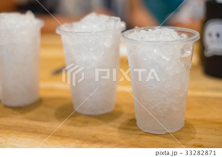 Ice in white plastic cup on wooden table 33282871