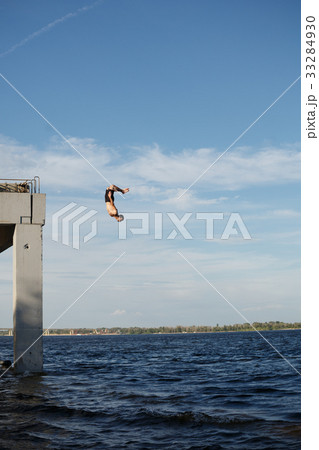 Man jumping into sea from pier 33284930