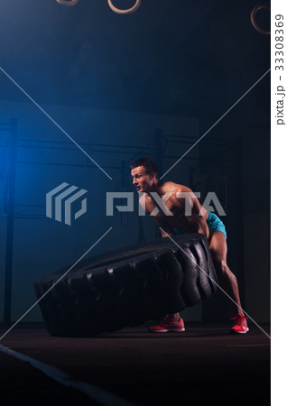 Muscular fitness man working out with tire in gym. 33308369