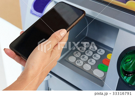 Woman holding mobile phone at an ATM. Woman holding mobile phone at an ATM. 33316791