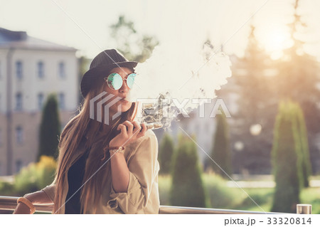 Pretty young hipster woman in black hat vape ecig 33320814
