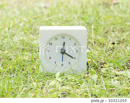 芝生の上の四角いシンプルな白い時計　12:20  33321203